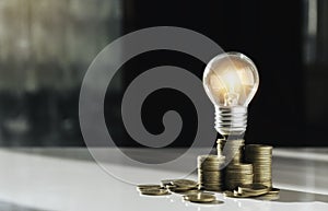 Coins and light bulb on table for saving money,energy concept