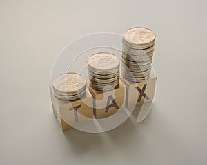 income tax increase with coins money stack on wooden cubes on a table