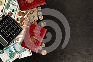 Coins and paper money and two international passports lie on a black wooden table