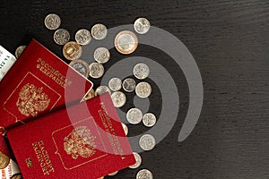 Coins and paper money and two international passports lie on a black wooden table