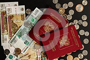 Coins and paper money and two international passports lie on a black wooden table