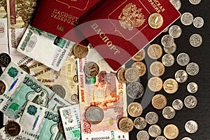 coins and paper money and two international passports lie on a black wooden table