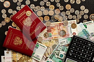 Coins and paper money and two international passports lie on a black wooden table