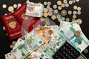 Coins and paper money and two international passports lie on a black wooden table