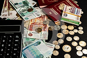 Coins and paper money and two international passports lie on a black wooden table