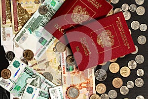 Coins and paper money and two international passports lie on a black wooden table