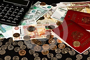 Coins and paper money and two international passports lie on a black wooden table