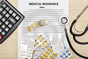 Coins, pills, stethoscope and calculator laying on the blank of