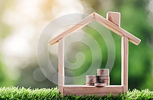 Coins placed is in a model house on the grass. planning savings money of coins to buy a home