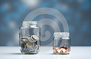 Coins saved in two separate glass jars. Income sharing concept for spending and savings