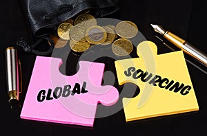 Coins are scattered on the black surface, there is a pen and puzzles on which it is written - GLOBAL SOURCING