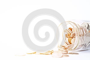 Coins scattered from glass jar on white background
