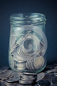 Coins spilling out of a glass bottle