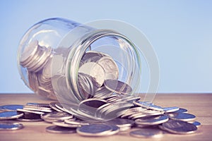 Coins spilling out of a glass bottle