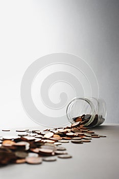 Coins spilling out of jar on its side in studio