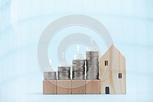 Coins stack in front of wooden home and arrow business, Save money concept, Property investment, house loan, reverse mortgage, gol