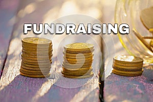 Coins stack on the wooden table with FUNDRAISING text.