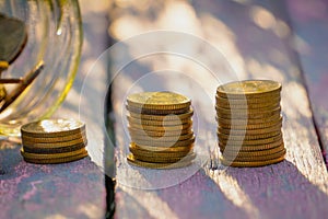 Coins stack on the wooden table with nature background.