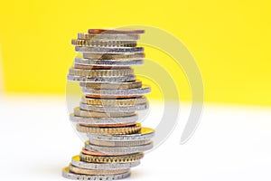 Coins stacked on each other in different positions on a yellow and white background