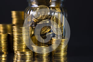 Coins stacks and gold coin money in the glass jar on dark background, for saving for the future banking finance concept