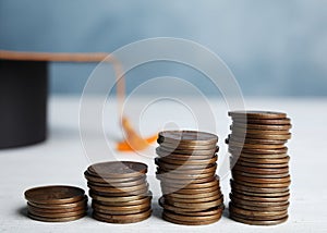 Coins and student graduation hat on wooden table. Tuition fees concept