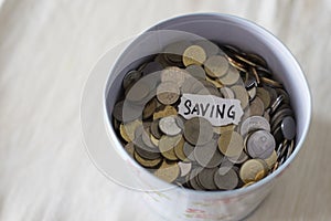 Coins in tin with a notes written by the word `saving`.