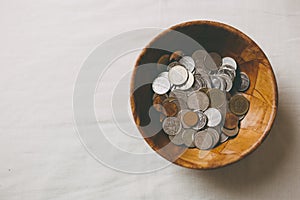 Coins in a wooden bowl, donate and give concept.