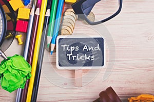Coins and word TIPS AND TRICKS on wooden desk