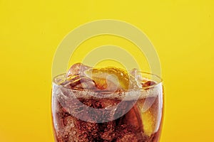 Coke glass full of liquid and ice with lemon