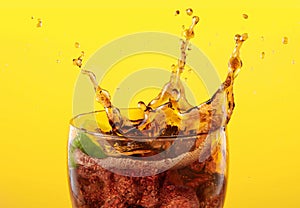 coke glass full of liquid and ice with splash