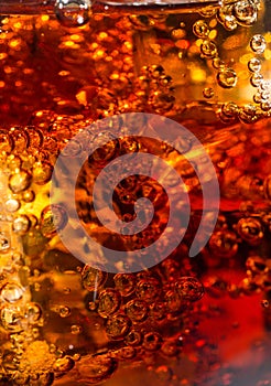 Cola in glass with ice and a bubbles of gas.