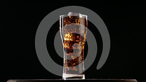 Cola with ice. Large glass of cold coke with ice cubes rotating.