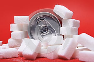 Cola refreshing drink can and lot of white sugar cubes representing the big amount of calories