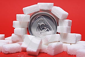 Cola refreshing drink can and lot of white sugar cubes representing the big amount of calories