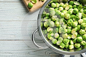 Colander with Brussels sprouts on wooden background, top view.