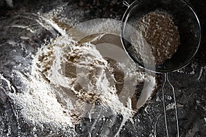 Colander with flour on the table. Stainless Steel Fine Mesh Strainer Colander Flour Sieve with Handle on dark background poudered