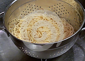 Colander of steaming hot spaghetti draining