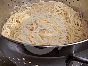 Colander of steaming hot spaghetti draining