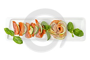 Cold appetizer of raw red fish slices with lemon. Appetizing popular dish. Top view. Isolated on a white background