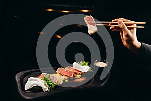 Cold appetizer of tuna and Chinese chopsticks on a black background