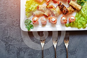 Cold appetizers, canapes and rolls of fish, eggplant and ham, decorated with fresh herbs