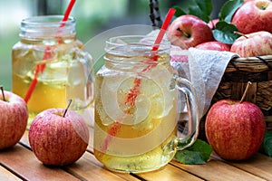 Cold apple juice with fresh apples outdoors on table