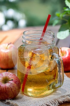 Cold apple juice in glass jar and fresh red apples