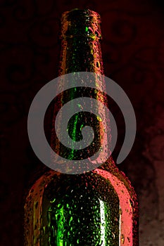 Cold beer bottle with drops on black
