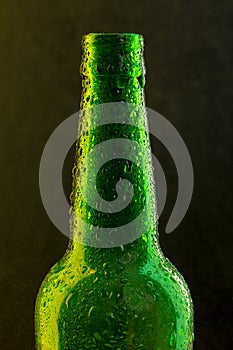 Cold beer bottle with drops on black