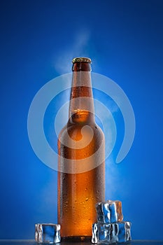 Cold beer bottle with drops on blue