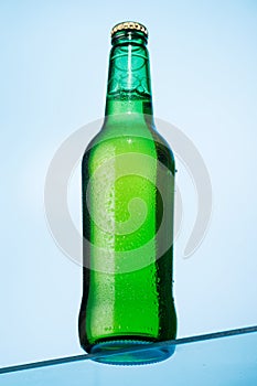 A cold beer bottle standing on a glass table