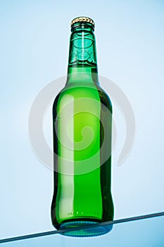 A cold beer bottle standing on a glass table