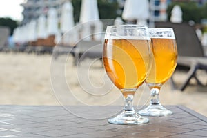 Cold beer in glass on beach. Space for text