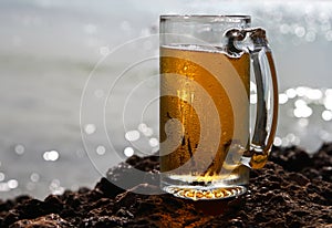 Cold beer glass on a cliif, shiny sea background